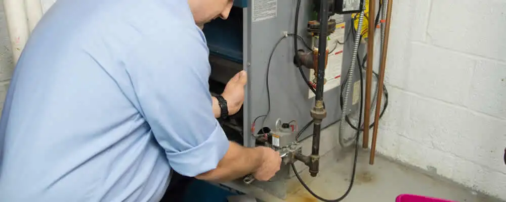 Furnace repair technician inspecting and servicing a home heating system in El Paso, TX
