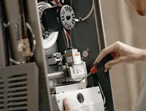 Furnace repair technician inspecting internal components and wiring in El Paso, TX