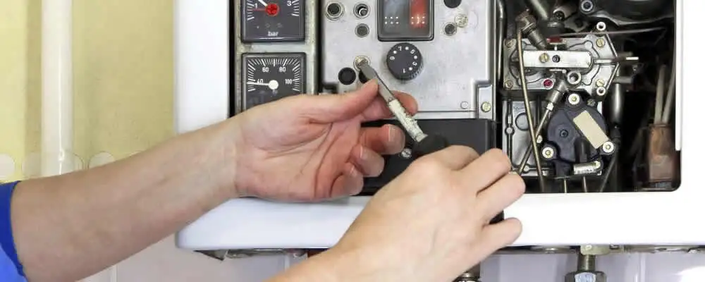 Heating repair technician adjusting boiler controls and components in El Paso, TX