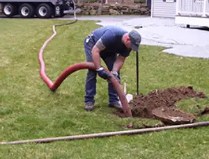 Septic pumping technician servicing a residential septic tank with a vacuum hose in El Paso, TX