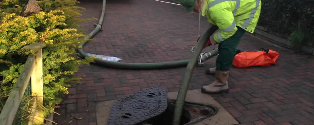Septic tank cleaning technician servicing a septic tank with a vacuum hose in El Paso, TX