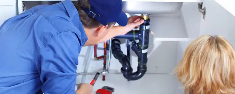 Plumber repairing under-sink drain pipes and fittings in El Paso, TX